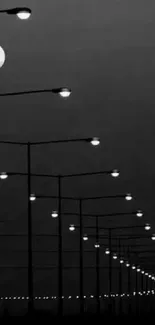 Black and white wallpaper with moonlit street lamps at night.