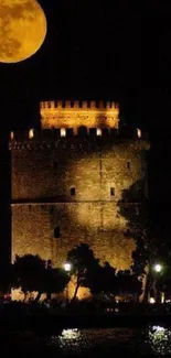 Tower under full moon with golden light reflecting on water.