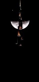 Moonlit city skyline with glowing tower against a black sky.