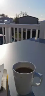 A tranquil scene of a coffee cup and book on a sunlit balcony table.