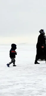 Mother and child walking on a snowy landscape in winter.