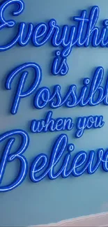 Neon sign saying 'Everything is Possible when you Believe' on a blue wall.
