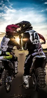 Motocross riders on dirt bikes at sunset under a vibrant sky.