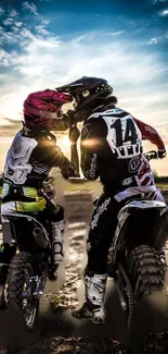 Pair of motocross riders enjoy the sunset on dirt bikes with dramatic skies in background.