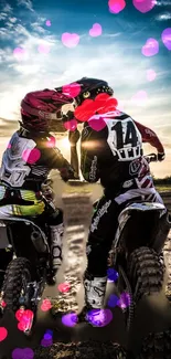 Two motocross riders embrace at sunset.