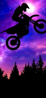 Silhouette of a motocross rider jumping against a purple galaxy sky.