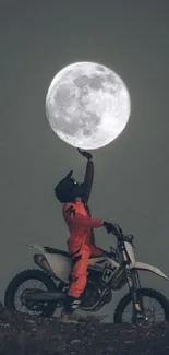 Motocross biker reaching towards a large full moon in a dramatic nighttime setting.