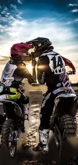 Two motocross riders sharing a moment under a vibrant sunset.