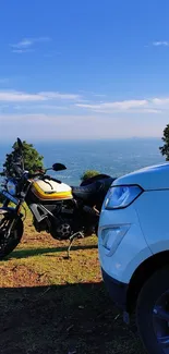 Motorbike and car overlooking a scenic blue sky landscape.