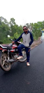 Person posing with motorbike on open road.