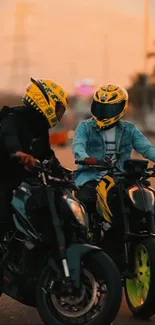 Two motorbike riders at sunset with vibrant helmets.