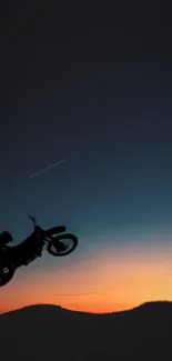 Motorbike performs daring stunt against a vivid sunset sky.