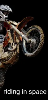 Motocross biker performing a stunt on a black background wallpaper.