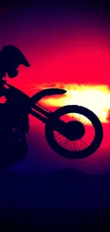 Silhouette of a motorbike against a crimson sunset sky, creating an energetic and dynamic scene.