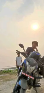 Man on a motorcycle at sunset with scenic horizon.