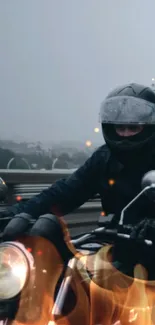 Motorcyclist rides through vibrant flames on a scenic road.