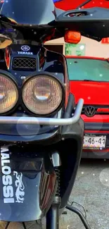 Close-up of motorcycle in front of red car, vibrant wallpaper.