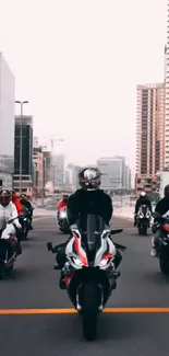 Group of motorcyclists riding through a city on a clear day.