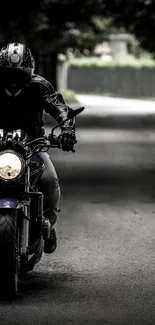 A motorcycle rider in black gear cruises down an urban alley.