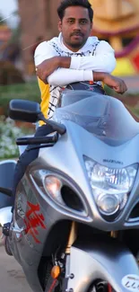 Man posing with sleek motorcycle in vibrant setting.