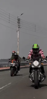 Motorcyclists riding on a gray road under a muted sky.