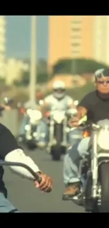 Group of bikers riding motorcycles down a sunny road.