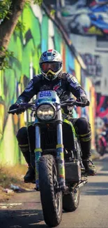 Motorcyclist rides through vibrant graffiti-lined urban street.