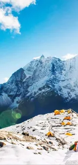 Snowy mountain peaks with tents and a clear blue sky.