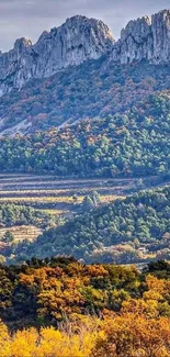 Mountain landscape with autumn foliage and rugged peaks under a serene sky.