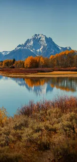 Majestic mountain with autumn trees and reflection on a tranquil lake.