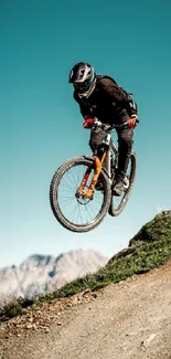 Mountain biker jumping on a dirt trail with a scenic mountain backdrop.