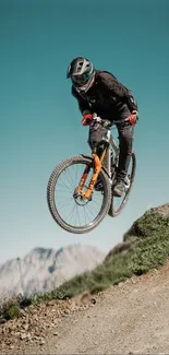 Mountain biker mid-air on a trail with mountains in background.