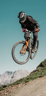 Mountain biker in mid-air against a teal sky, showcasing adventure and skill.