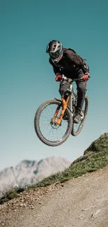 Mountain biker performing a jump on a dirt trail against a scenic backdrop.