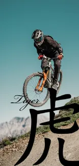 Cyclist on mountain bike with artistic calligraphy, set against blue sky.