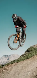 Cyclist jumps on a mountain biking trail with scenic mountain view.