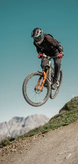 Mountain biker jumping with scenic mountain backdrop.