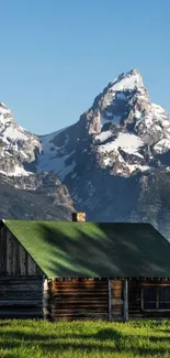 Rustic cabin with snowcapped mountains in the background.