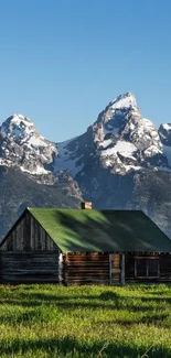 Rustic cabin with mountain backdrop and green fields.