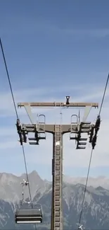 A cable car ascending over mountains under a clear blue sky.