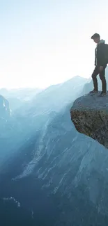 Lone hiker standing on mountain cliff with scenic view.