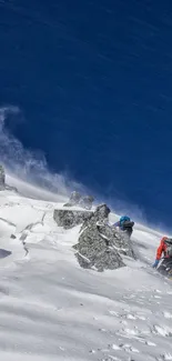 Climbers conquering a snowy mountain under a vivid blue sky.