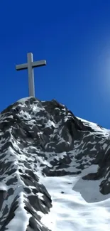 Snowy mountain peak with a cross under vibrant blue sky.