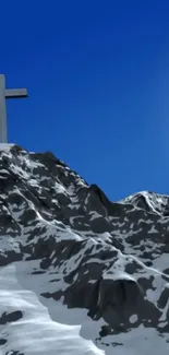 Snowy mountain peak with a prominent cross under a clear blue sky.