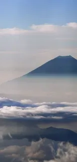 View of a mountain peak surrounded by a sea of clouds with a clear blue sky.