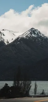 Snow-capped mountains and tranquil lake view under a cloudy sky.