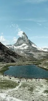 Majestic mountain peak and tranquil lake under a clear blue sky.