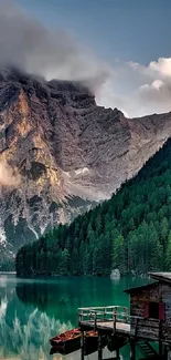 Serene mountain lake with lush green forest and cloudy peaks.