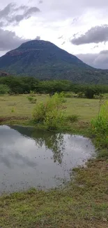 Scenic mountain view with pond and clouds on a mobile wallpaper.