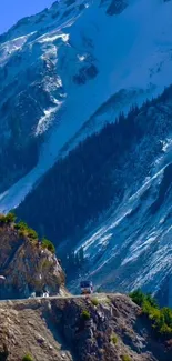 Mountain road view with snowy peaks and greenery.